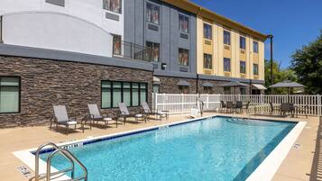 Un hotel con piscina, area relax all'aperto e facciata in pietra.