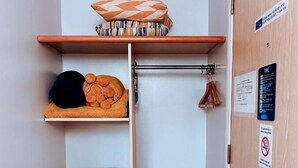 Un baño pequeño y ordenado, con un perchero, una repisa con artículos de aseo y una cesta de mimbre.