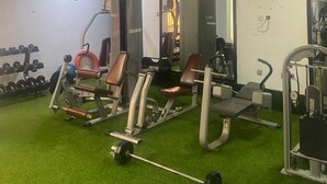 A gym with various exercise equipment, including weight machines and a barbell. - 3J's Hotels & Apartments (Abuja)