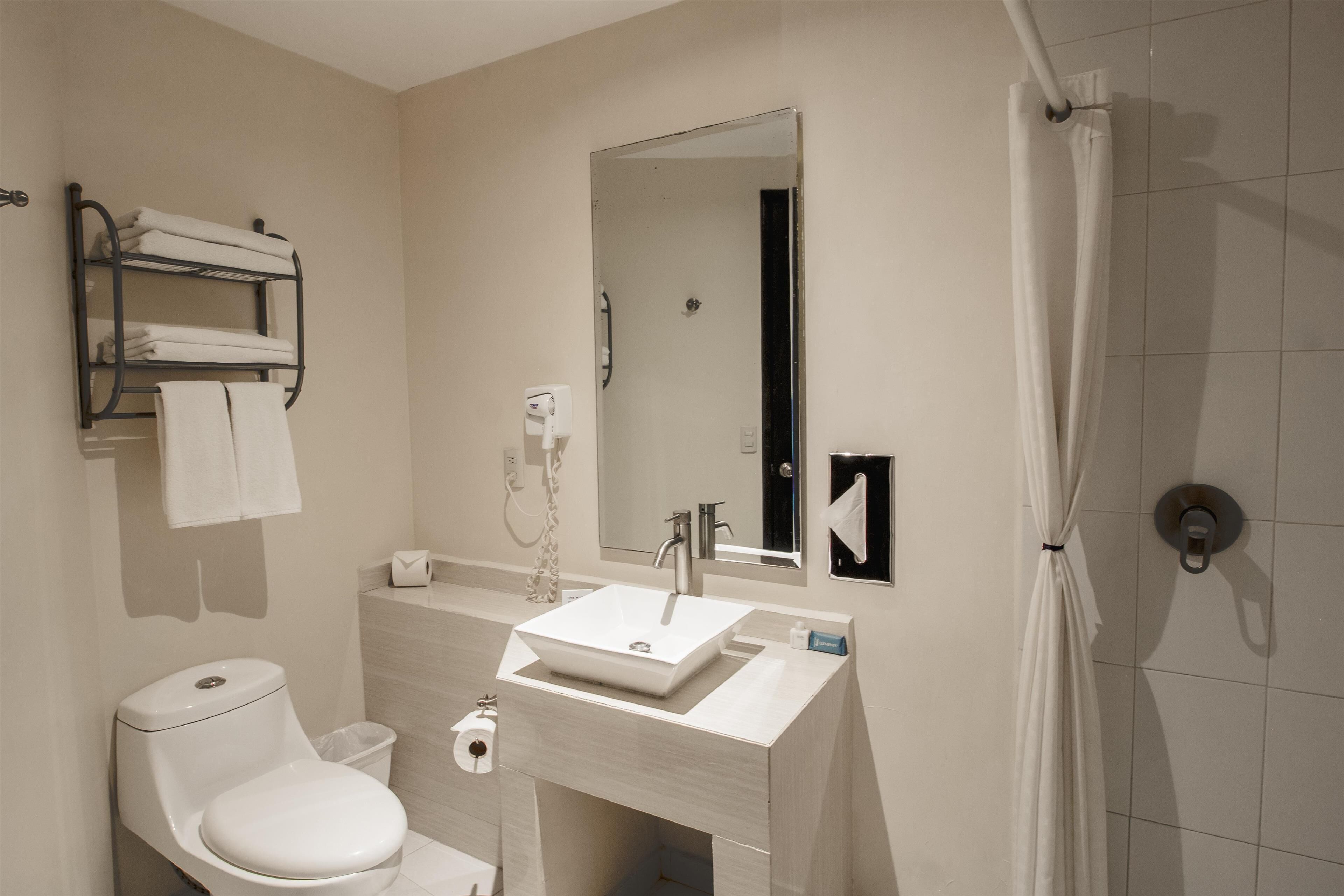 A modern bathroom with a white sink, toilet, and shower curtain.