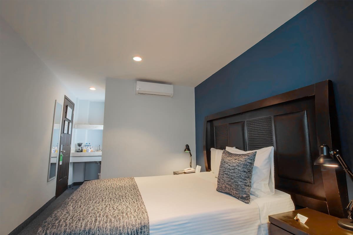 A hotel room with a bed, bedside lamp, and a view of the bathroom.