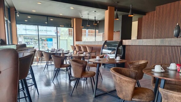 A modern cafe interior with leather chairs and tables, large windows, and a coffee machine. - Best Western Real Tula Express (Tula de Allende)
