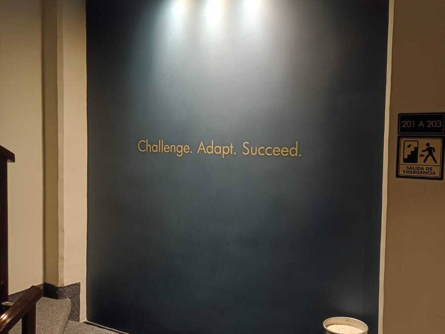A staircase with a motivational quote on the wall, a fire extinguisher, and emergency exit signs.