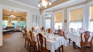 A dining area with multiple tables set for a meal, surrounded by wooden chairs. - O Canada House (Vancouver)