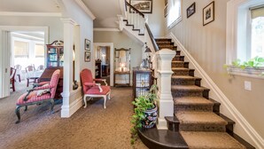 A spacious living room with a staircase, a dining area, and a hallway leading to another room. - O Canada House (Vancouver)