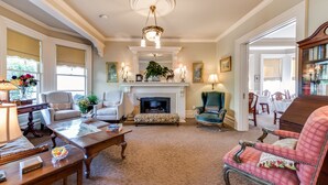 A spacious living room with a fireplace, comfortable seating, and a piano. - O Canada House (Vancouver)