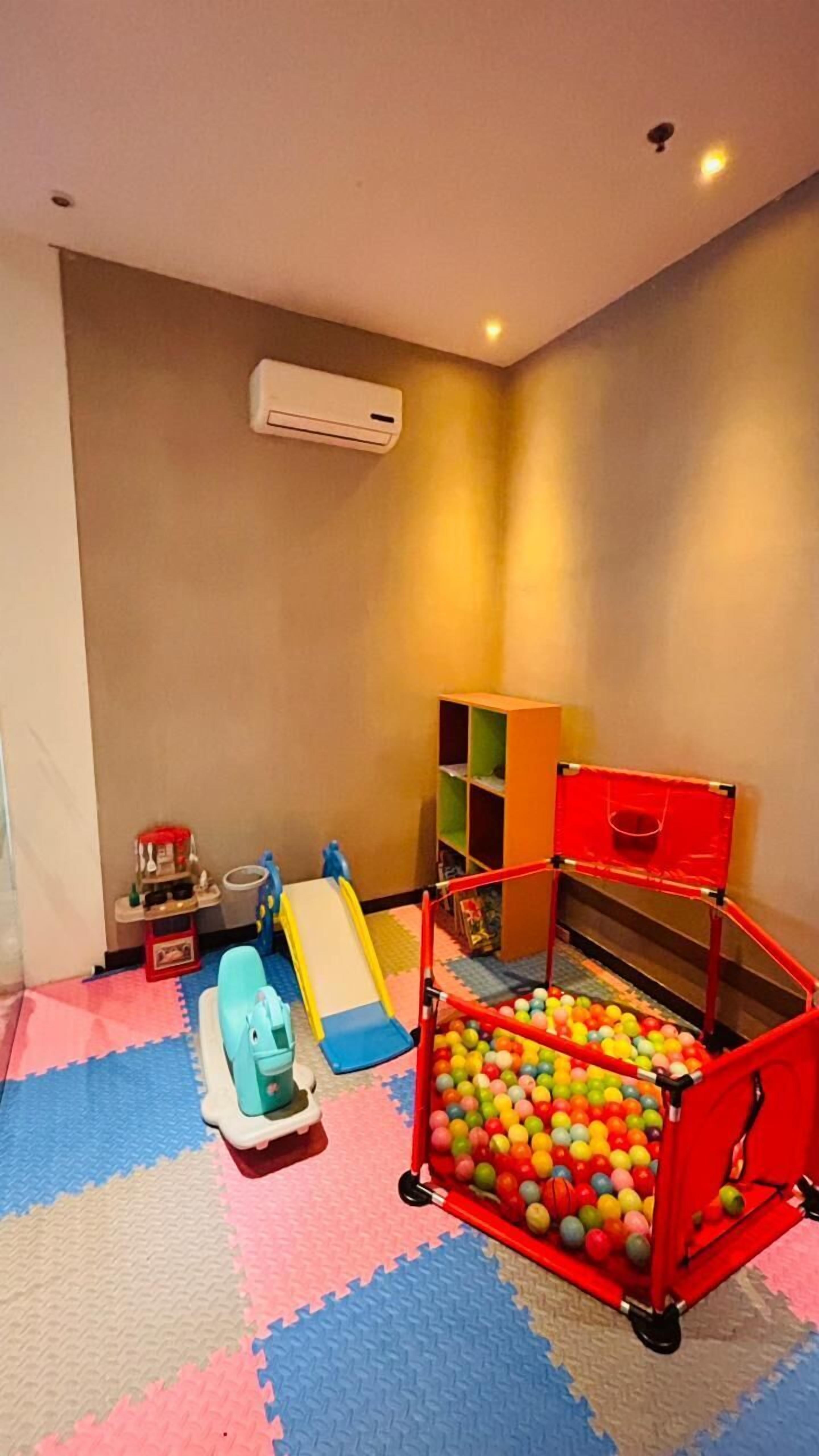 Zona de juegos con piscina de pelotas, tobogán y estructura de juegos pequeña.