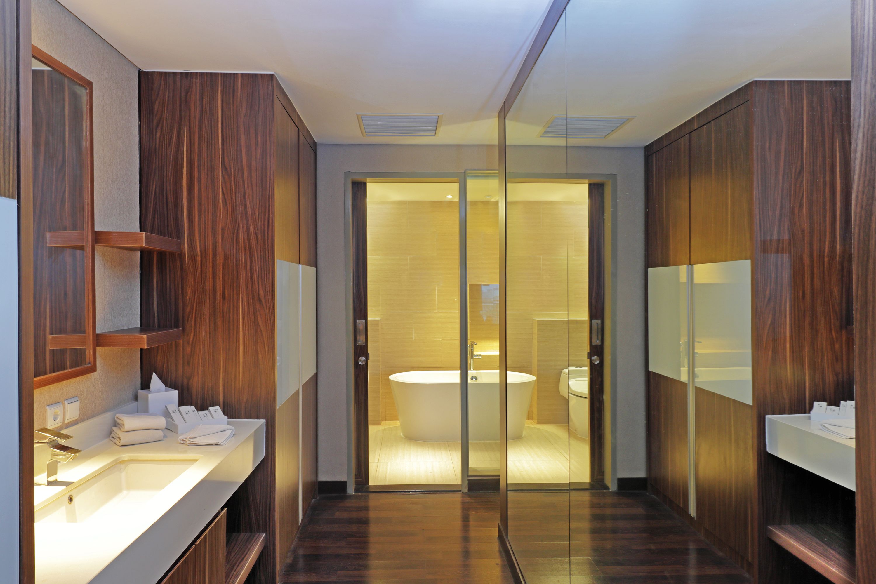 A modern bathroom with a wooden vanity, a large mirror, and a glass-enclosed shower area.