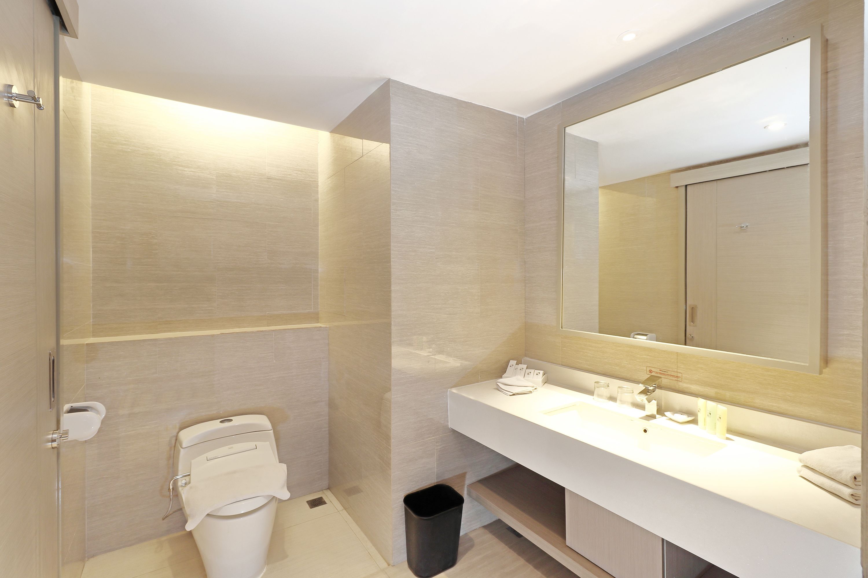 A modern bathroom with a large mirror, a white sink, and a toilet.