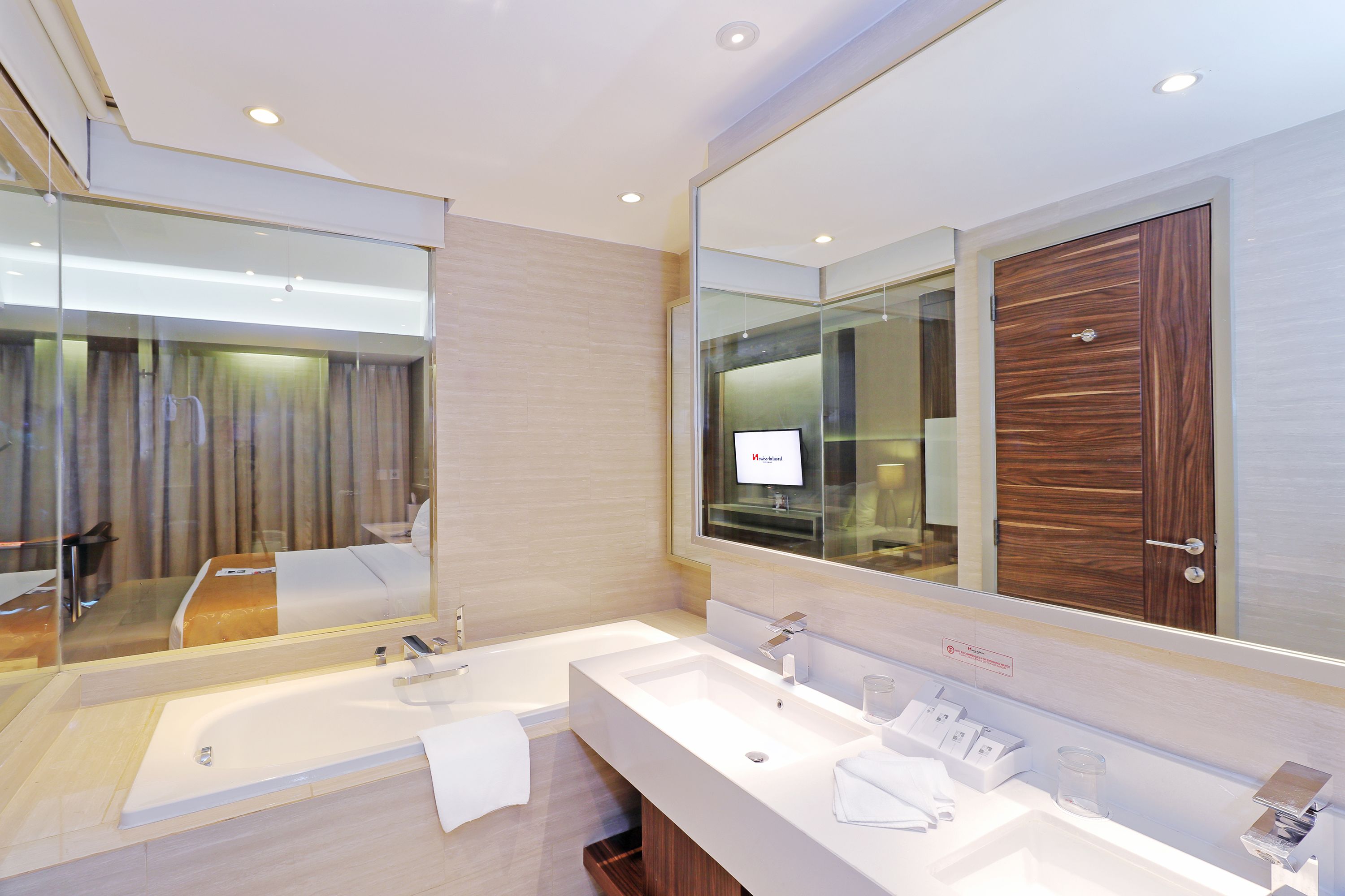 A modern bathroom with a large mirror, two sinks, and a bathtub.