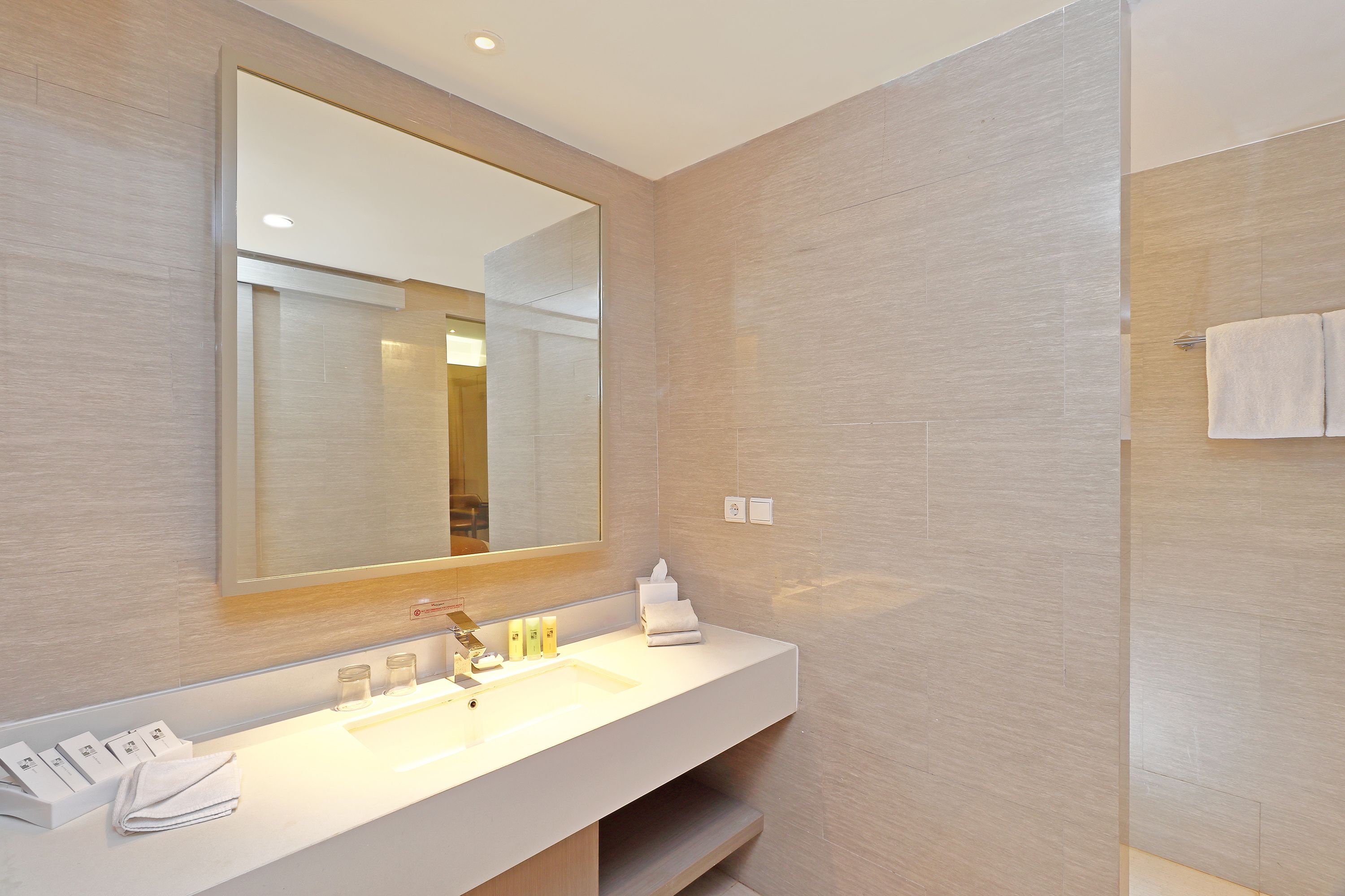 A modern bathroom with a large mirror, a white sink, and a towel rack.