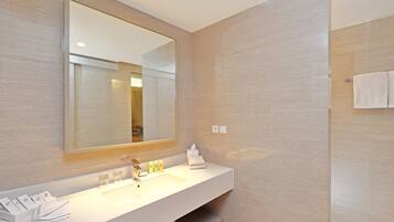 A modern bathroom with a large mirror, a white sink, and a towel rack.