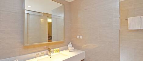 A modern bathroom with a large mirror, a white sink, and a towel rack.