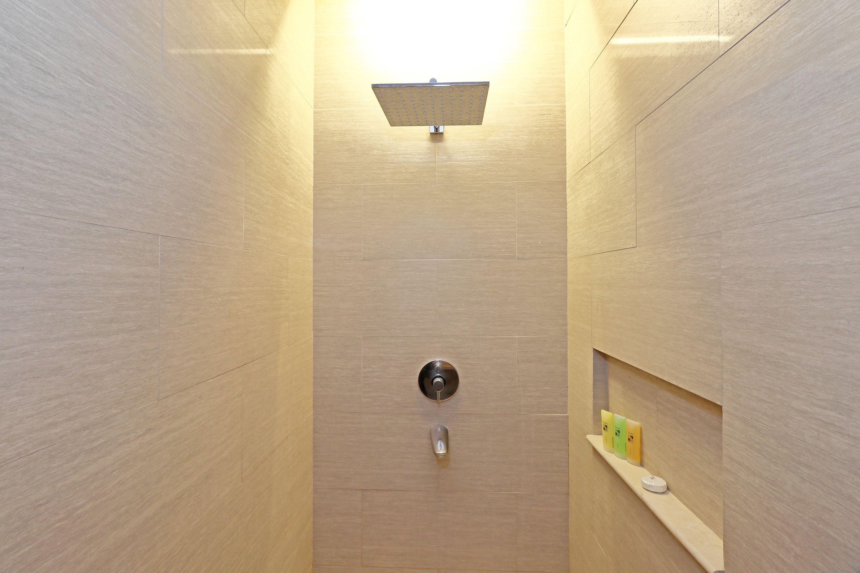 Un baño moderno con ducha, inodoro y un estante con artículos de aseo.