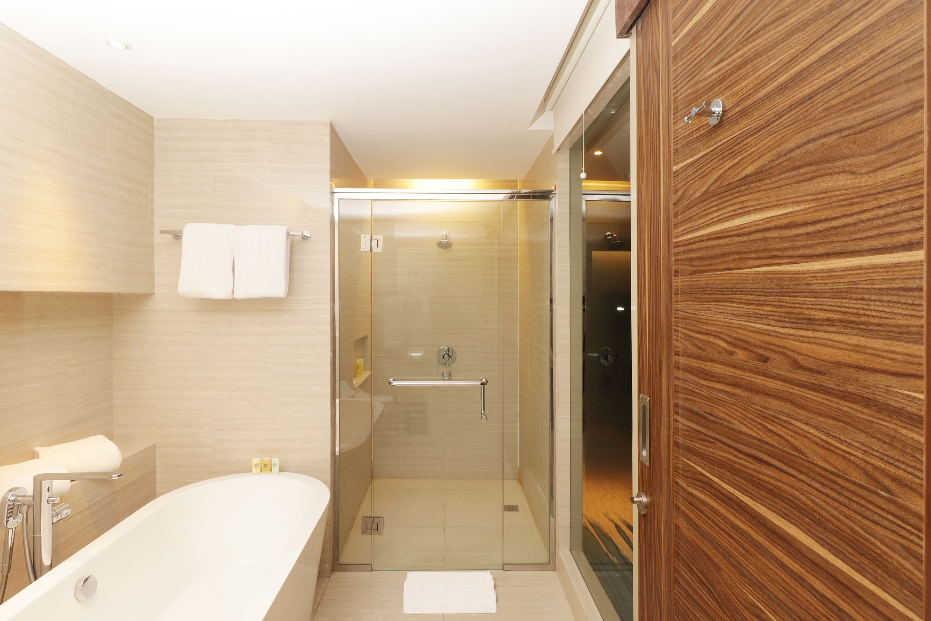 Une salle de bain moderne avec une douche à parois de verre, une baignoire sur pieds et un meuble-lavabo en bois.