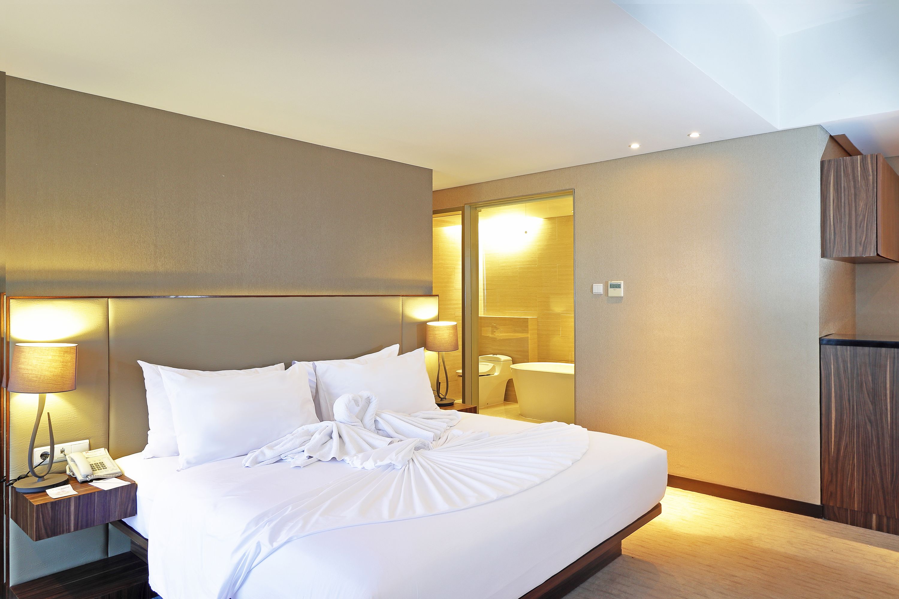 A hotel room with a large bed, bedside lamps, a telephone, and a mirror.