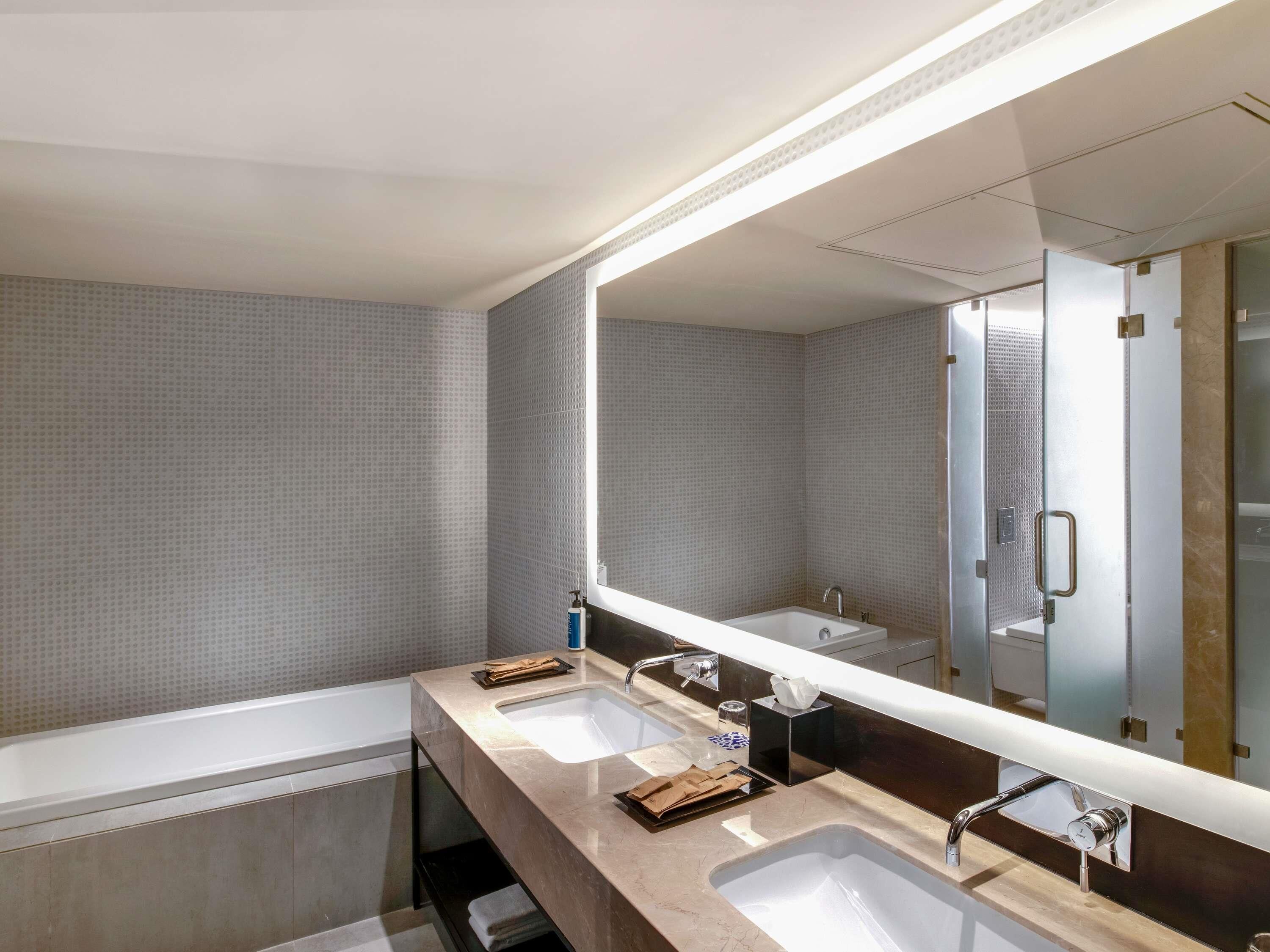 A modern bathroom with two sinks, a large mirror, and a shower area.