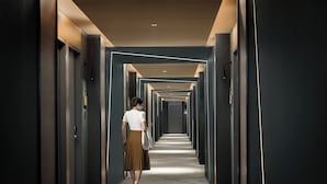 Un pasillo con puertas a ambos lados, una persona caminando y un techo con iluminación empotrada.