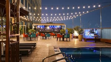 An outdoor bar area with string lights, a pool, and outdoor seating.