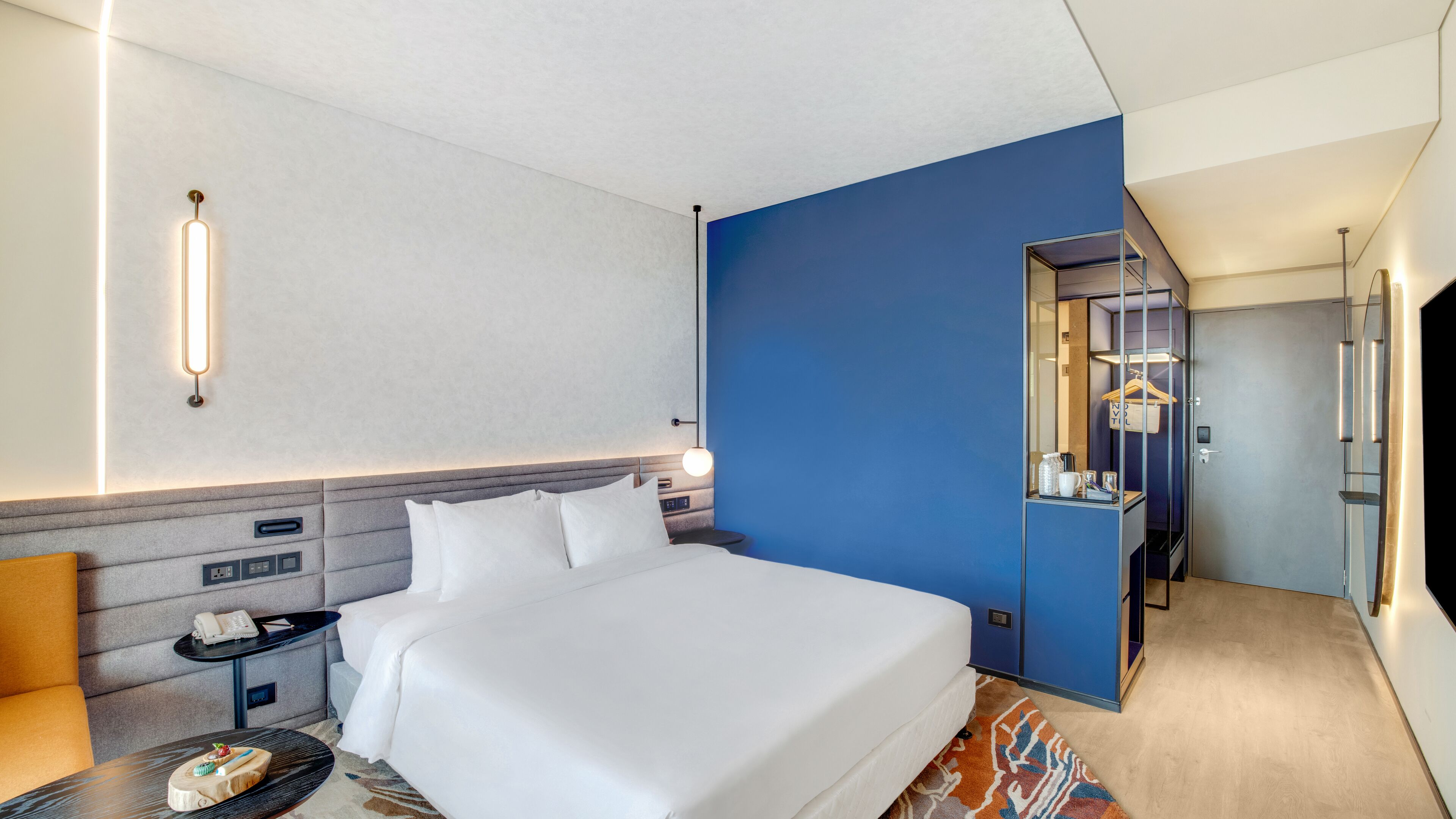 A hotel room with a large bed, bedside tables, a desk, and a wardrobe.