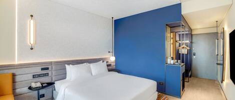 Una habitación de hotel con una cama grande, mesitas de noche, un escritorio y un armario.