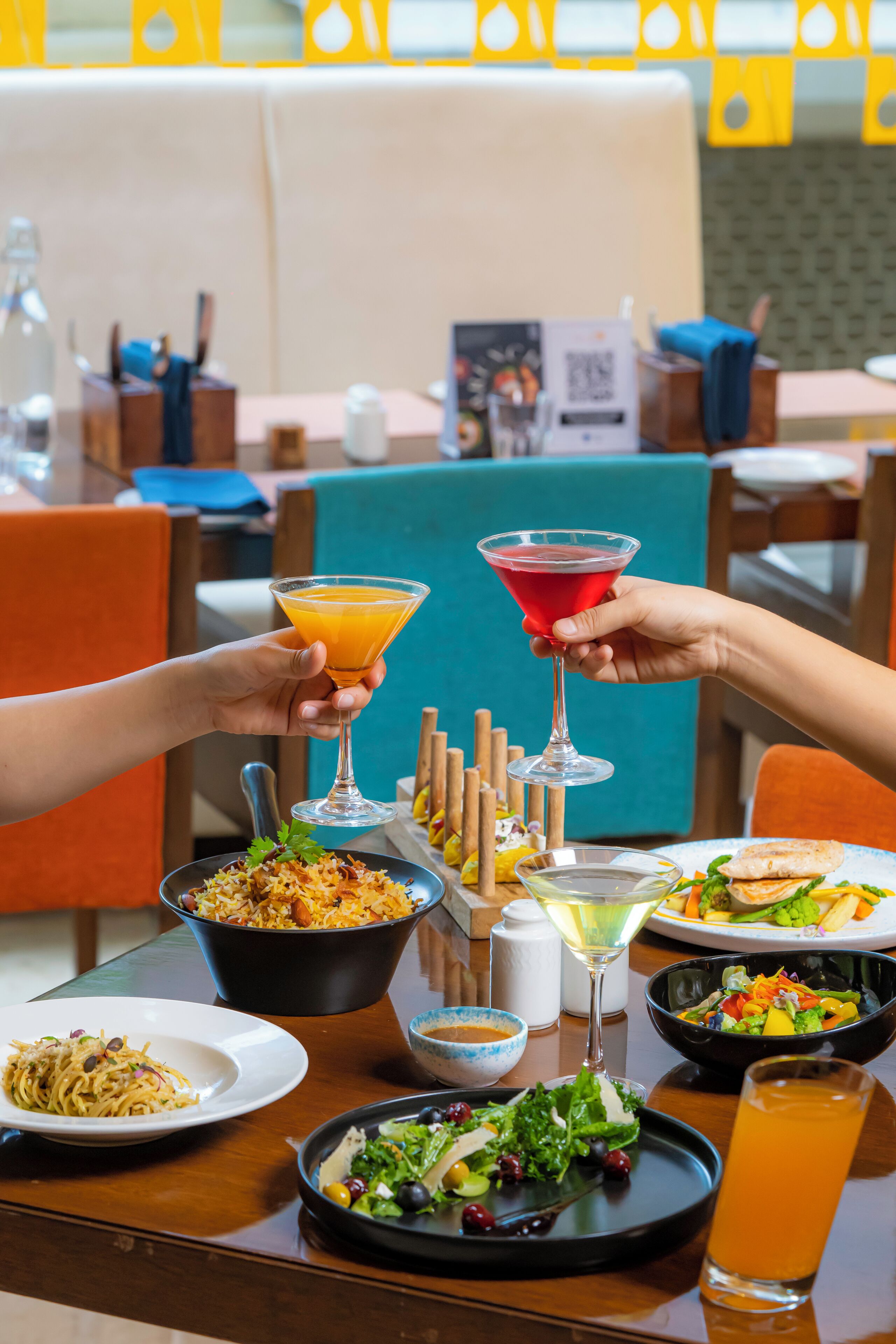 A dining table with various dishes, including pasta, salad, and a martini glass.