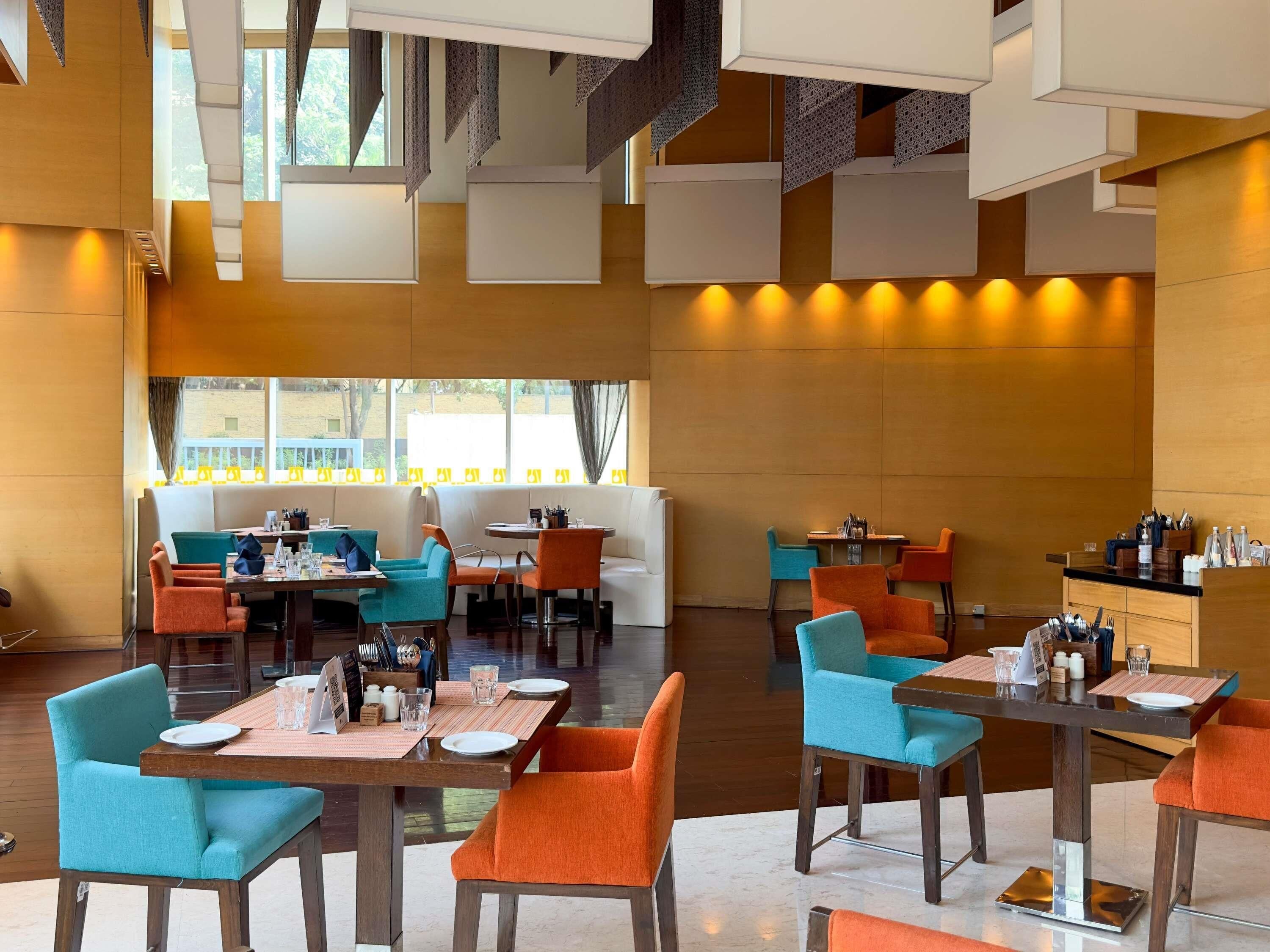 A modern restaurant with high ceilings, multiple dining areas, and a view of the outside.