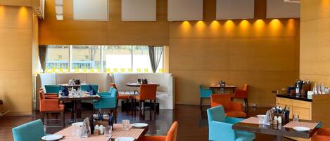 Un restaurante moderno con techos altos, varias zonas de comedor y vistas al exterior.