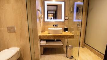 A modern bathroom with a glass shower enclosure, a white sink, and a marble countertop.