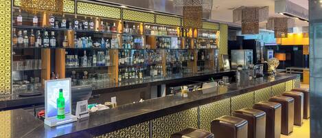 Una zona de bar con una barra larga, estantes llenos de botellas de licor y un código QR para pagos digitales.