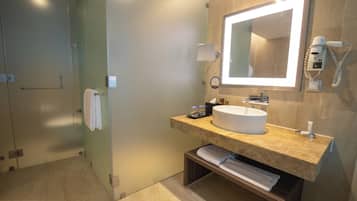 A modern bathroom with a large mirror, a sink, a towel rack, and a hairdryer.