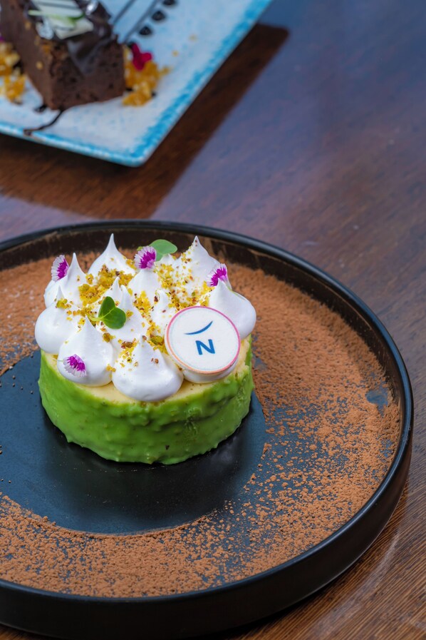 A dessert on a plate with a decorative element and a letter 'N'. - Novotel Pune Viman Nagar Hotel (Pune)