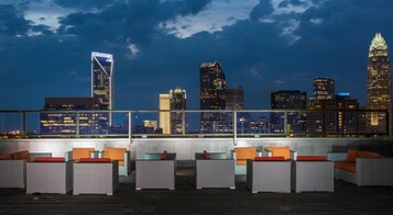 A rooftop terrace with outdoor seating and a city skyline view.
