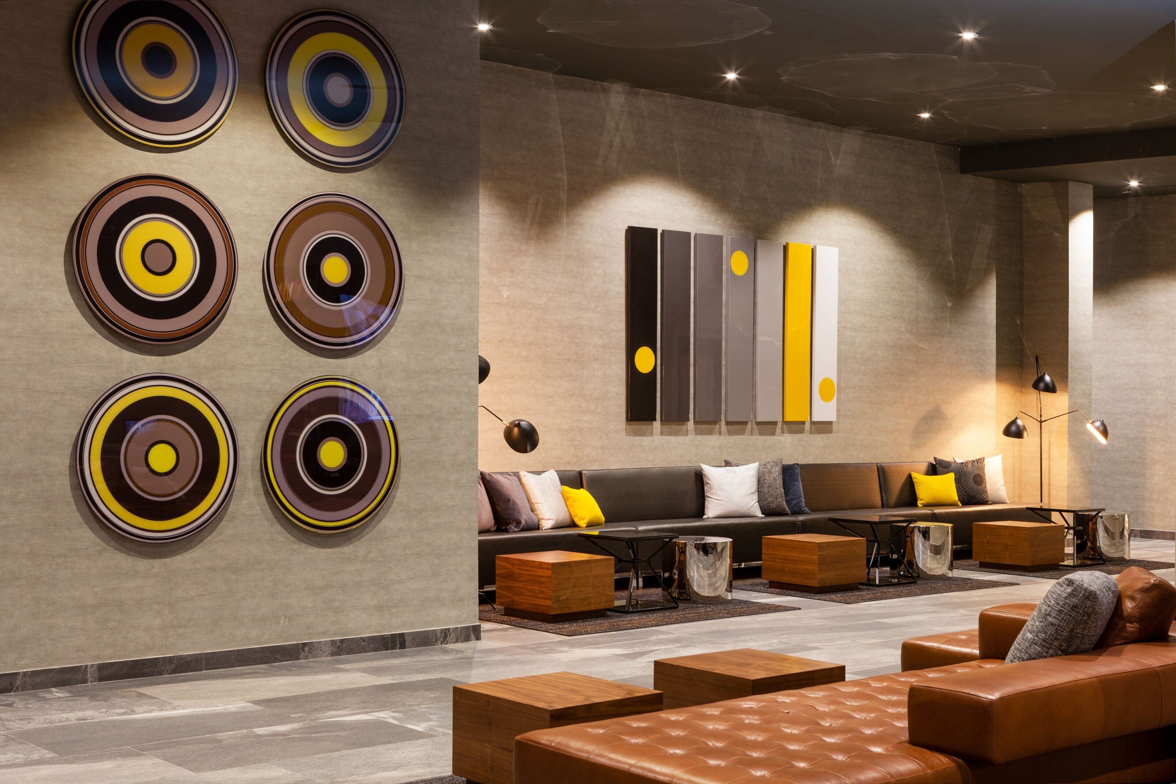 A modern lobby with a seating area, a wall with circular art, and a minimalist design.