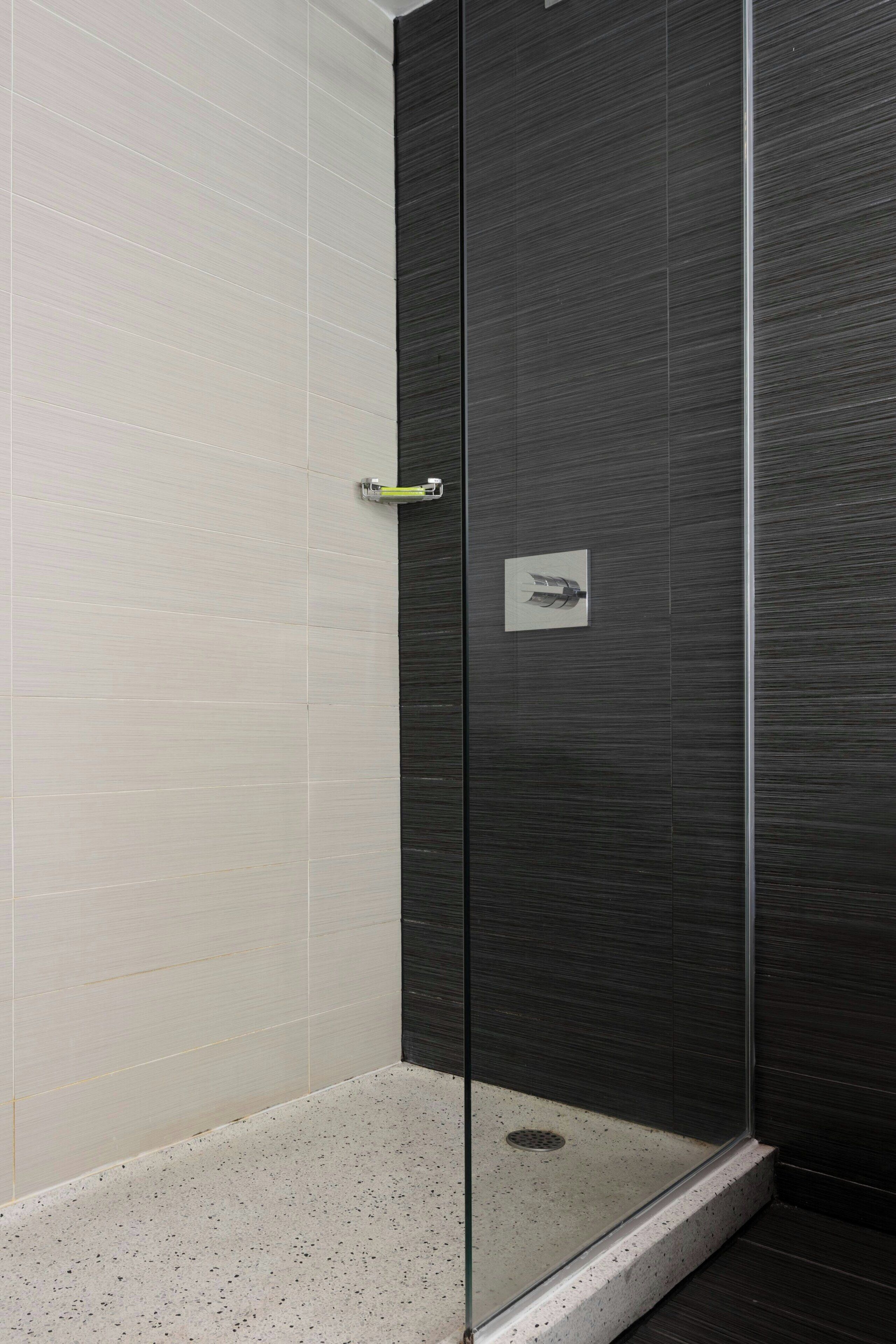 A modern shower enclosure with a glass door, a metal handle, and a small towel rack.