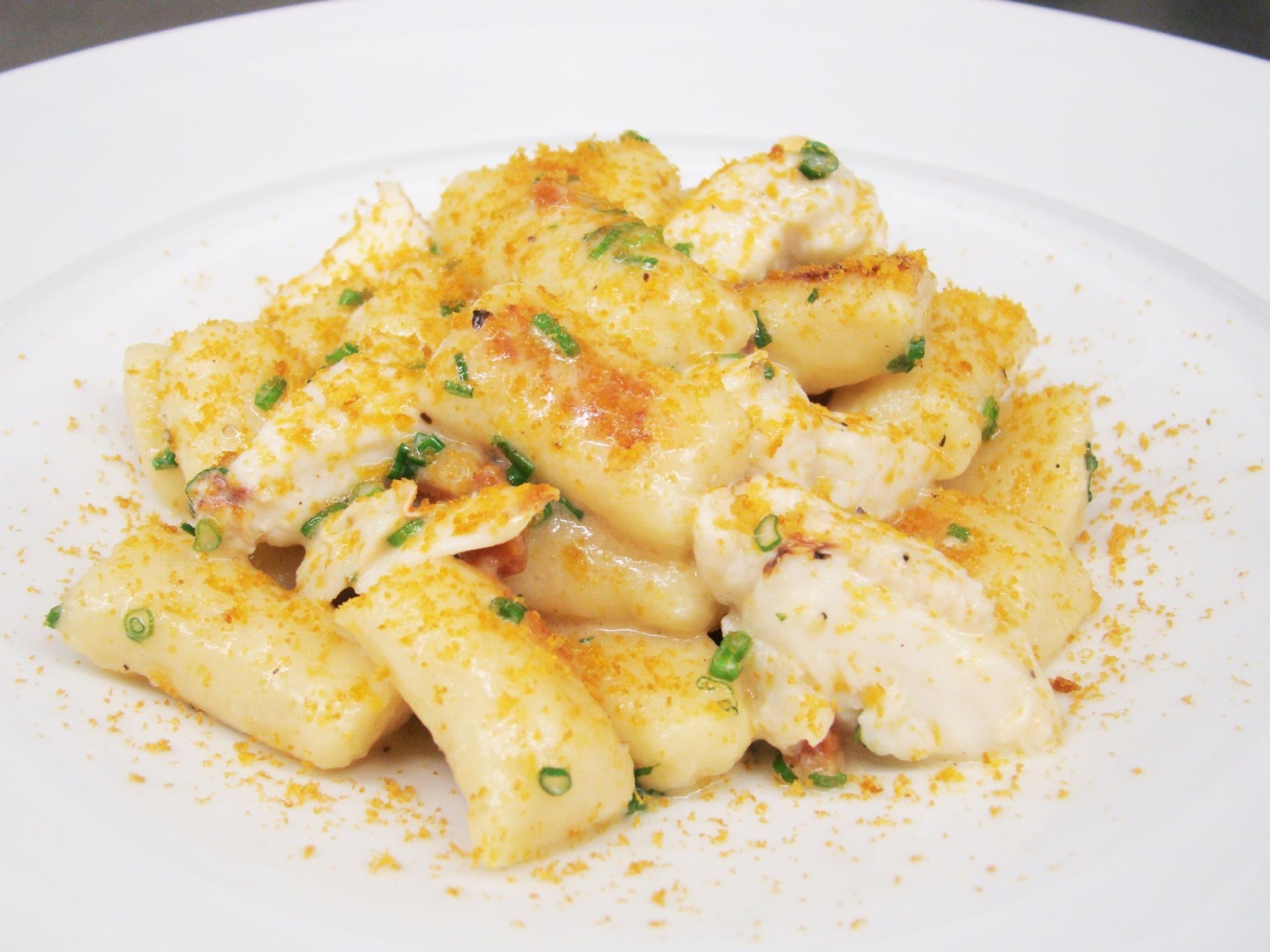 A plate of pasta with a creamy sauce, garnished with green herbs.