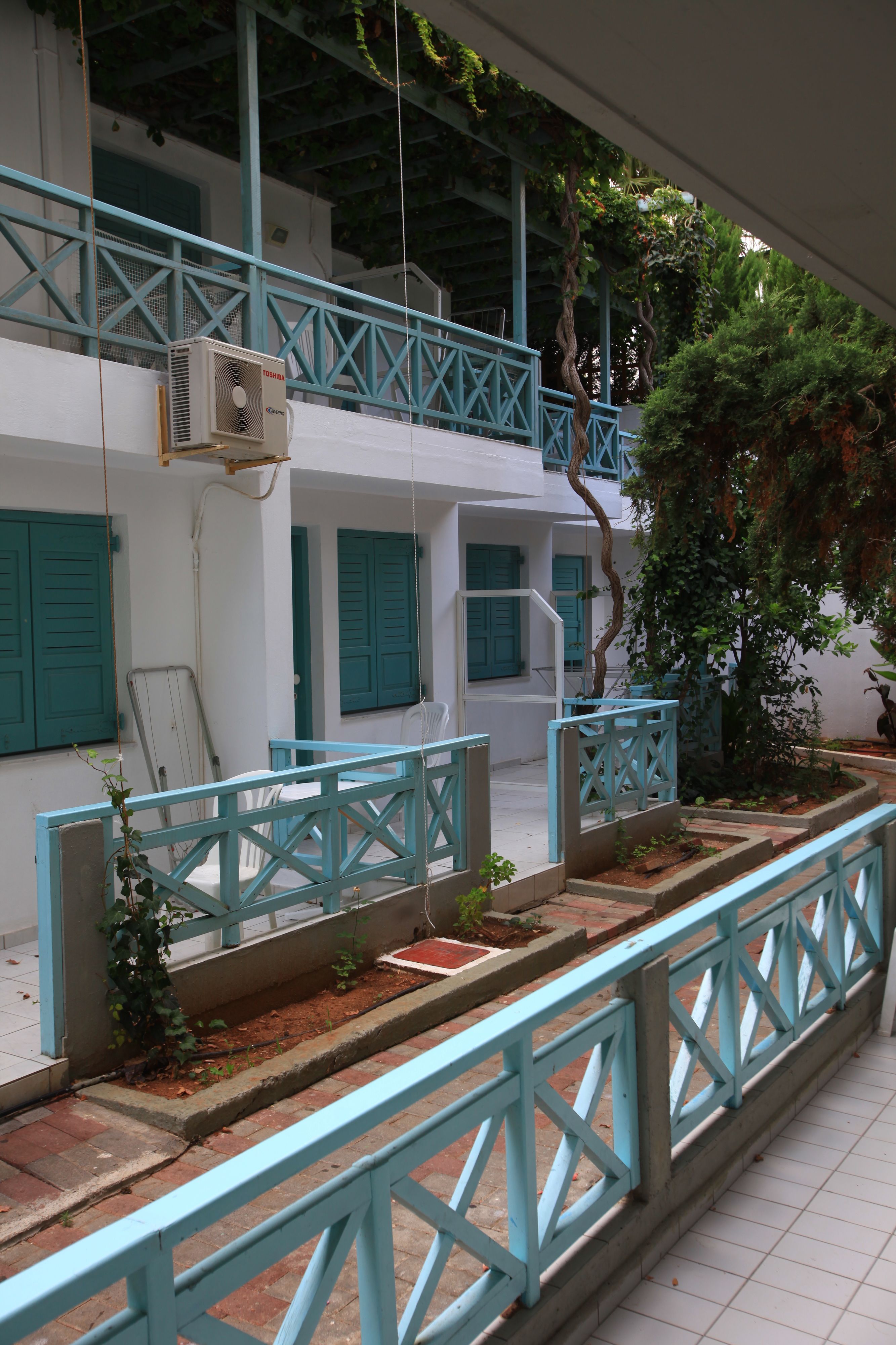 A building with a white facade, blue shutters, and a blue railing.