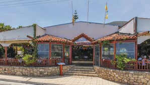 A Greek tavern with a tiled roof, stone walls, and outdoor seating. - Anatoli Apartments (Hersonissos)