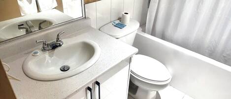 Un baño moderno con lavamanos, espejo, inodoro y bañera.