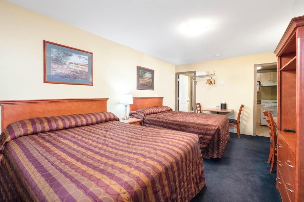 A hotel room with two beds, a desk, a chair, and a wardrobe.