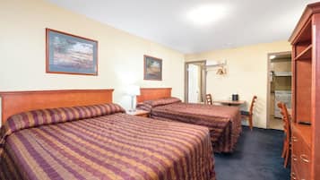 A hotel room with two beds, a desk, a chair, and a wardrobe.