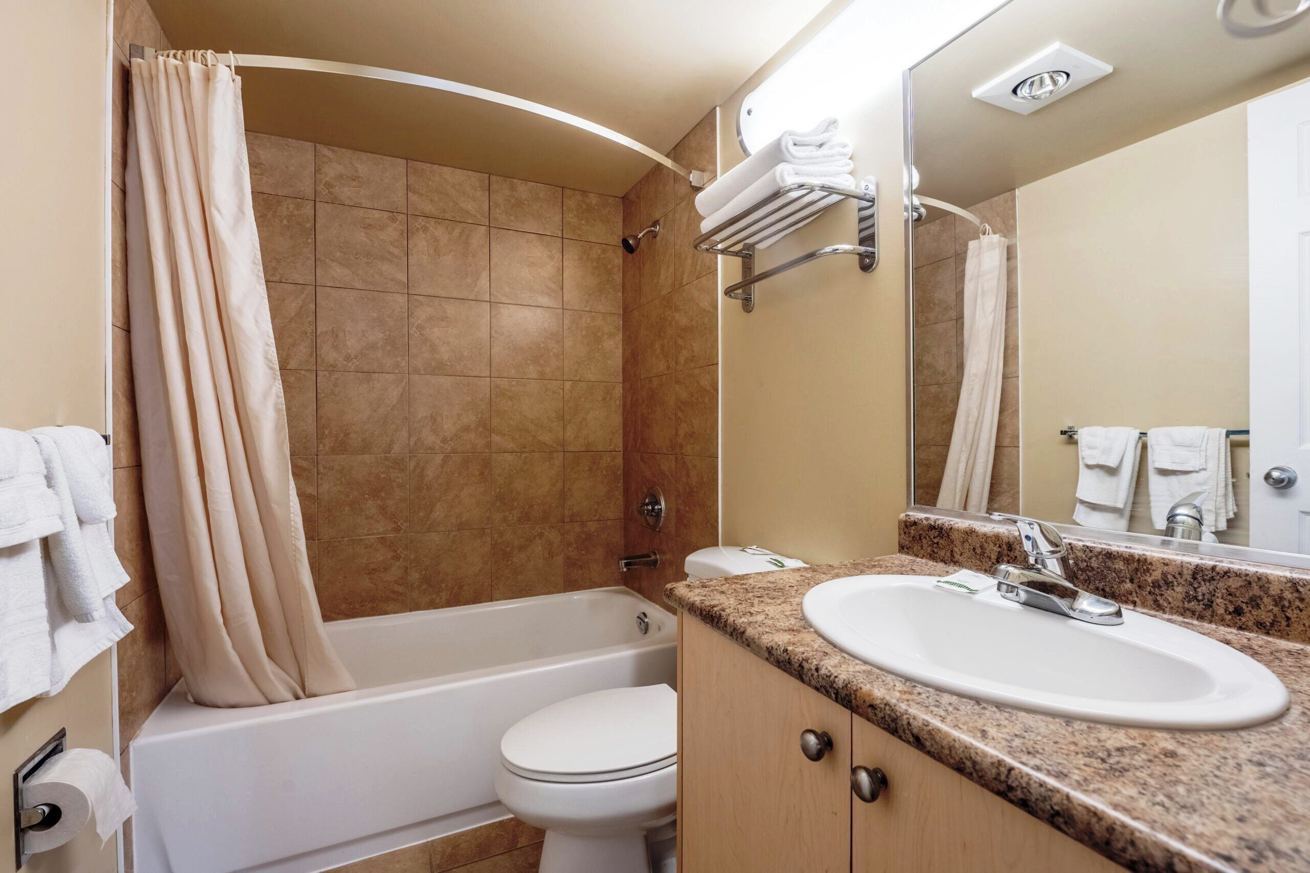 Ein Badezimmer mit Badewanne, Toilette, Waschbecken und Duschvorhang.