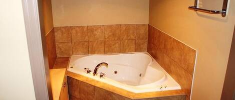 A bathroom with a large bathtub, a towel rack, and a door.