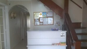 Un comptoir d’accueil avec un panneau d’affichage, un escalier et un couloir.