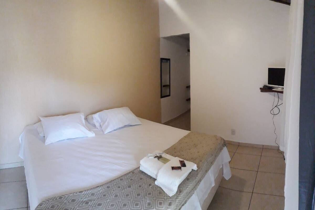 A hotel room with a bed, a TV mounted on the wall, and a small desk.