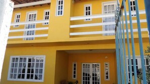 Un immeuble jaune à deux étages, doté de fenêtres à encadrement blanc et d’un balcon.