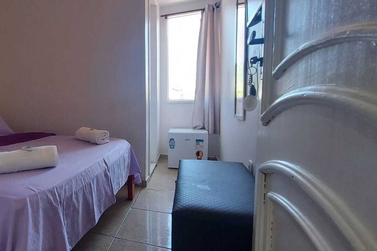A bedroom with a bed, a small table, a window, and a radiator.