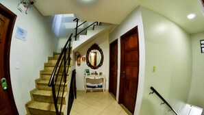 A staircase with a handrail, a small console table with a mirror, and a door with a wooden frame. - Pousada Fernandes (Arraial do Cabo)