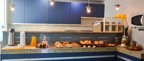 Cocina con armarios azules, encimera de granito y diversos alimentos para el desayuno.