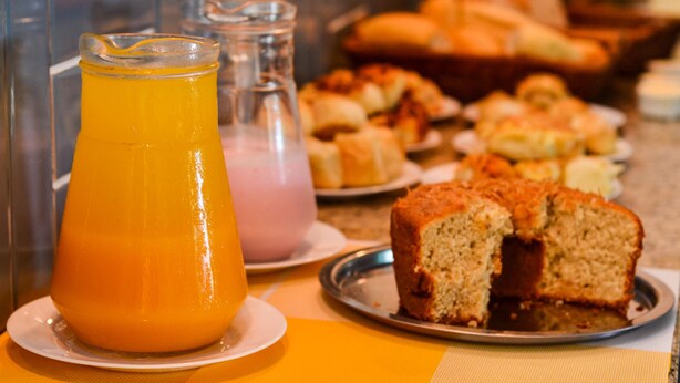 A breakfast buffet with various pastries and a glass of orange juice. - Pousada Fernandes (Arraial do Cabo)